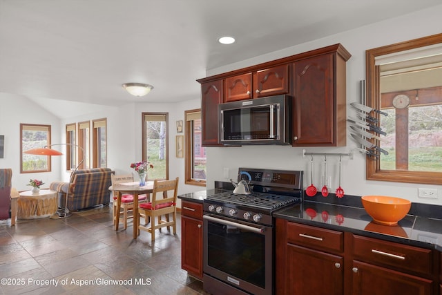 kitchen with dark countertops, stainless steel appliances, recessed lighting, and reddish brown cabinets