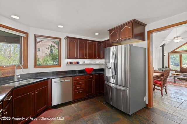 kitchen with stone tile floors, dark countertops, recessed lighting, a sink, and stainless steel appliances