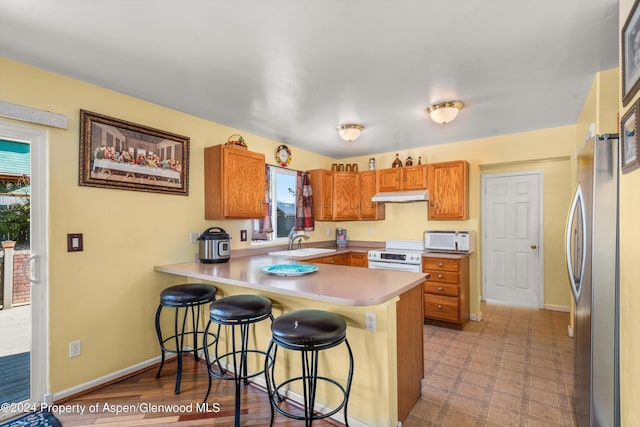 kitchen featuring sink, white appliances, kitchen peninsula, and a breakfast bar area