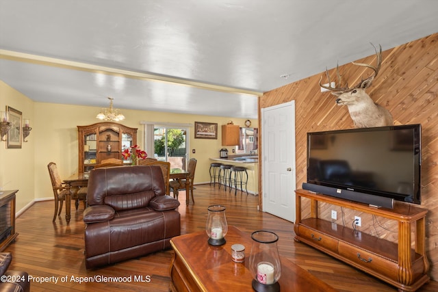 living room featuring hardwood / wood-style floors, wooden walls, and a notable chandelier