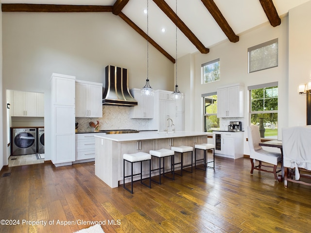 kitchen featuring a breakfast bar, dark wood finished floors, wine cooler, wall chimney exhaust hood, and independent washer and dryer