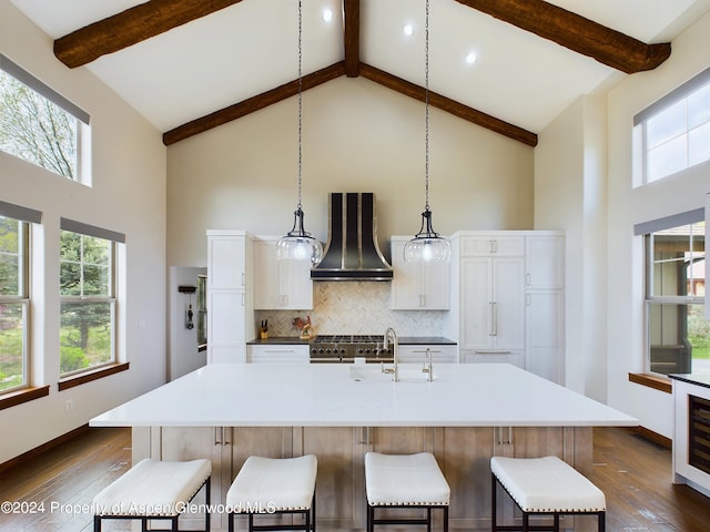 kitchen featuring decorative backsplash, high vaulted ceiling, wall chimney exhaust hood, and a sink