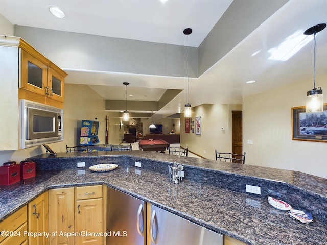 kitchen with decorative light fixtures, stainless steel microwave, glass insert cabinets, and open floor plan