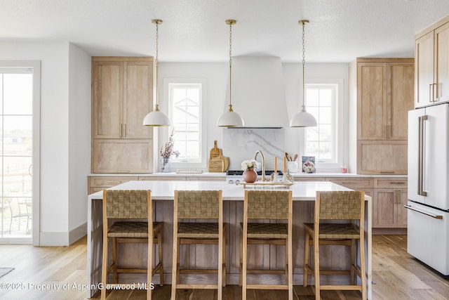 kitchen featuring a kitchen island with sink, high end fridge, and extractor fan