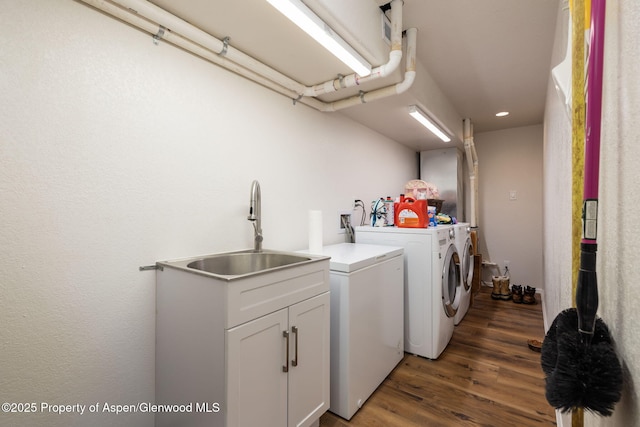 washroom featuring dark wood-type flooring, laundry area, a sink, and washer and clothes dryer