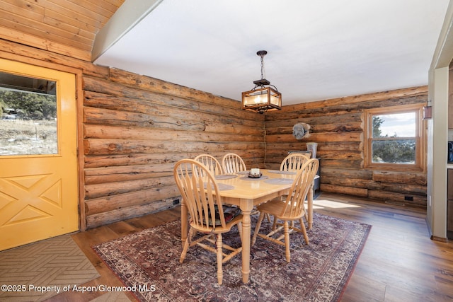 dining room with rustic walls and dark wood finished floors