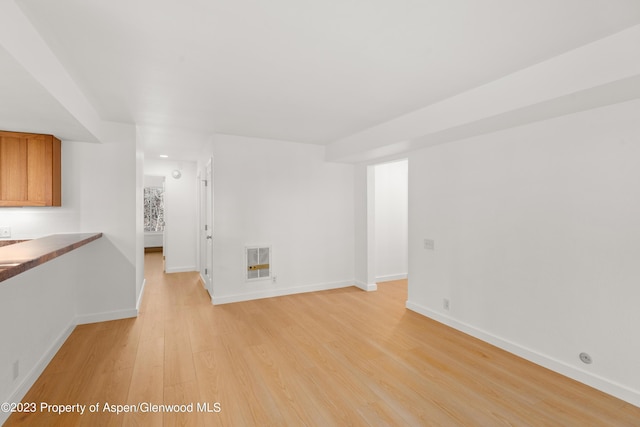 unfurnished living room featuring heating unit and light wood-type flooring