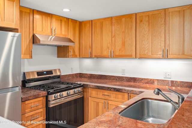 kitchen featuring dark stone countertops, sink, and stainless steel appliances