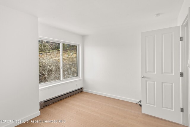 spare room with light wood-type flooring and a baseboard heating unit