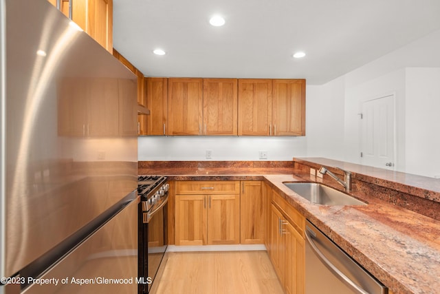 kitchen featuring light wood-type flooring, sink, stainless steel appliances, and stone countertops