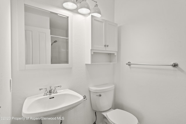 bathroom with tiled shower, toilet, and sink