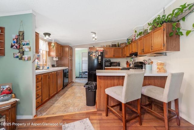 1137 Rose St, Craig, CO 81625 - kitchen with black appliances, a peninsula, light countertops, brown cabinetry, and a breakfast bar area