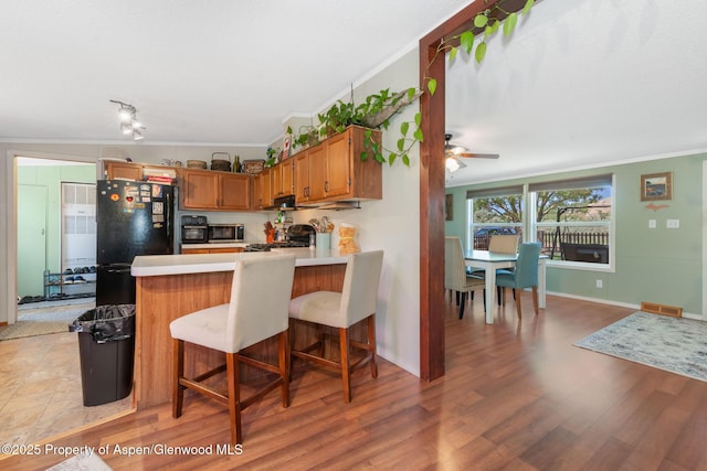 1137 Rose St, Craig, CO 81625 - kitchen featuring freestanding refrigerator, ornamental molding, stainless steel microwave, a peninsula, and light countertops