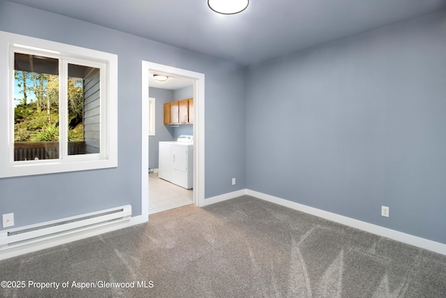 carpeted spare room with a baseboard heating unit, separate washer and dryer, and baseboards