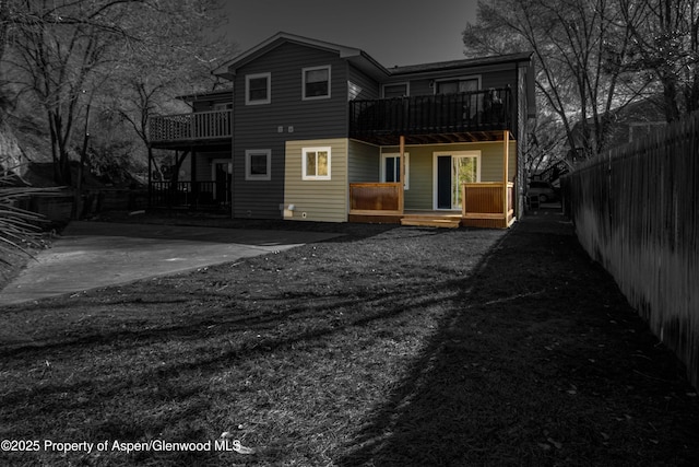 rear view of house with a balcony, fence, and a wooden deck