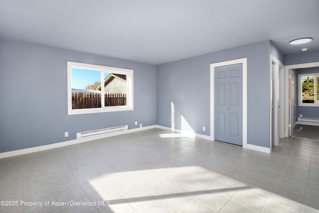 interior space with a baseboard heating unit, a closet, baseboards, and tile patterned flooring