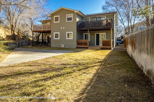 rear view of house featuring a yard, a deck, and fence