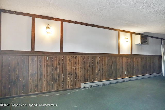 basement featuring baseboard heating, wooden walls, a wall mounted air conditioner, and a textured ceiling