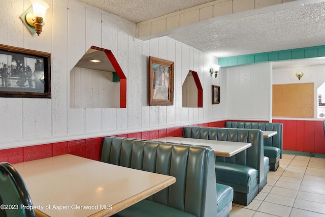 interior space featuring wooden walls, tile patterned flooring, and a textured ceiling