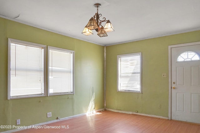 entryway with crown molding, a chandelier, and light hardwood / wood-style floors