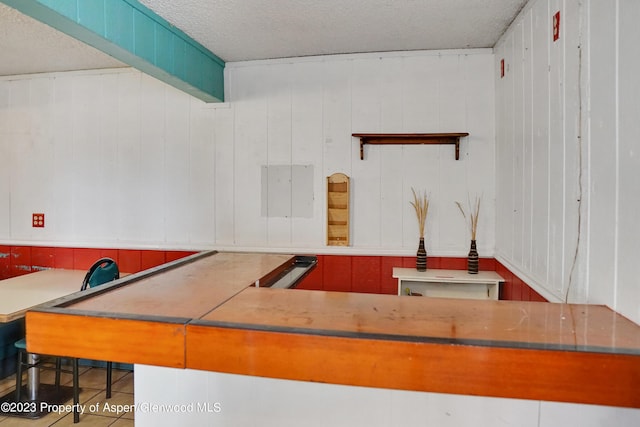 kitchen featuring wooden walls and a textured ceiling