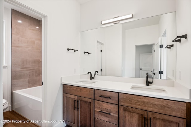 full bathroom with tiled shower / bath combo, vanity, and toilet