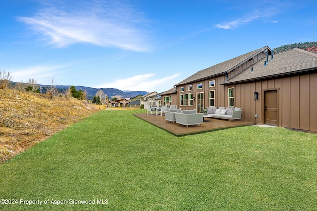 view of yard with outdoor lounge area and a deck with mountain view