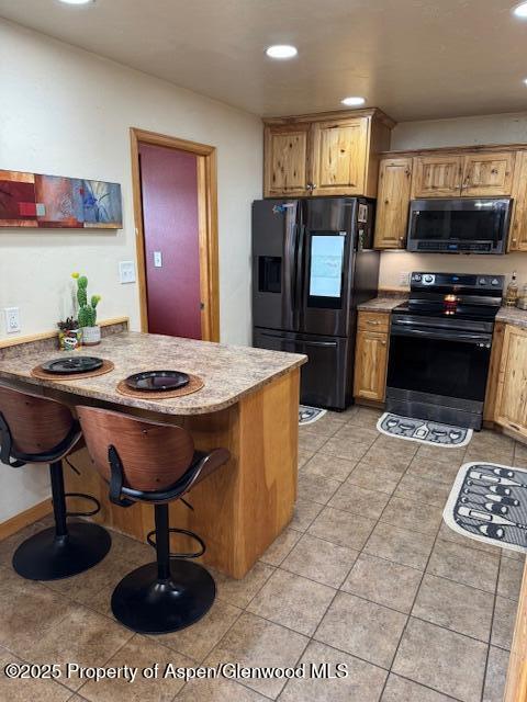 3695 W W 6th St, Craig, CO 81625 - kitchen featuring black appliances, recessed lighting, a breakfast bar, a peninsula, and light tile patterned floors