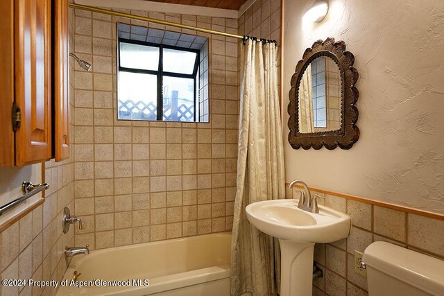 bathroom with shower / bath combination with curtain, tile walls, and toilet