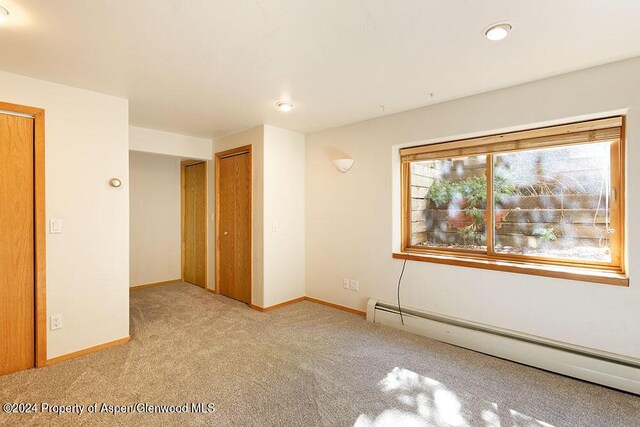 carpeted empty room featuring a baseboard radiator