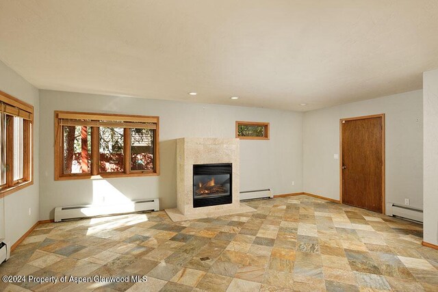 unfurnished living room with a fireplace and a baseboard heating unit