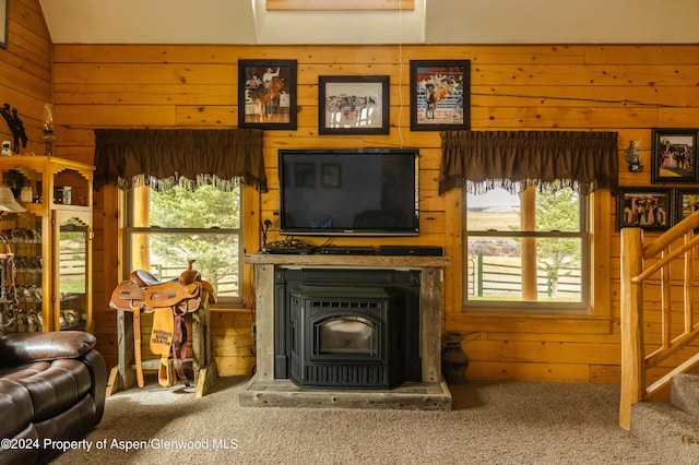 carpeted living room featuring a wood stove, wooden walls, a healthy amount of sunlight, and vaulted ceiling