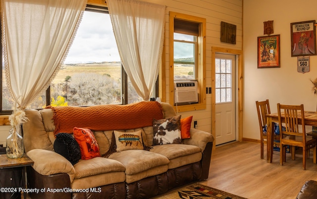 living room featuring wood walls, cooling unit, and light hardwood / wood-style floors