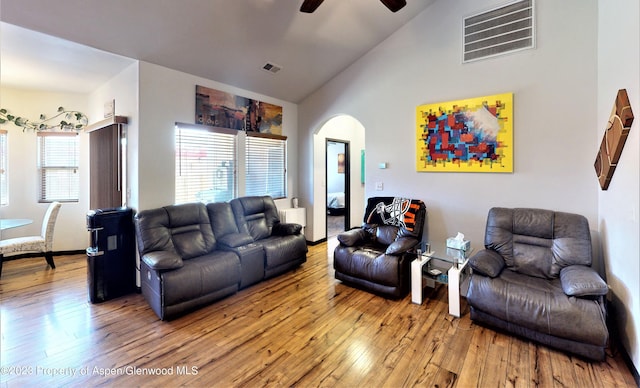 living room with a wealth of natural light, hardwood / wood-style floors, ceiling fan, and vaulted ceiling