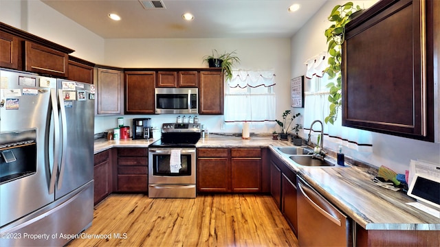 kitchen with sink, stainless steel appliances, and light hardwood / wood-style floors