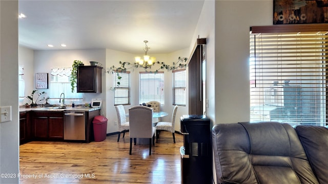 dining area with light hardwood / wood-style floors, sink, and a chandelier