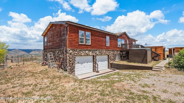 160 Mustang Mesa Trl, Rifle, CO 81650 - back of house with log veneer siding, stairway, a garage, stone siding, and a wooden deck