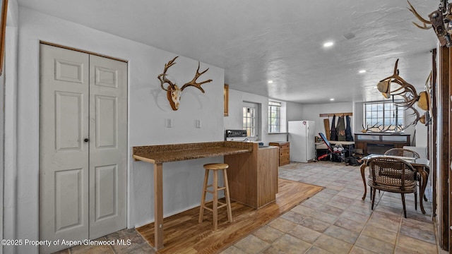 160 Mustang Mesa Trl, Rifle, CO 81650 - kitchen with freestanding refrigerator, a peninsula, recessed lighting, a kitchen breakfast bar, and dark countertops