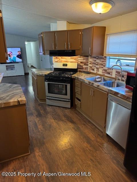 kitchen with stainless steel appliances, a sink, tasteful backsplash, extractor fan, and lofted ceiling