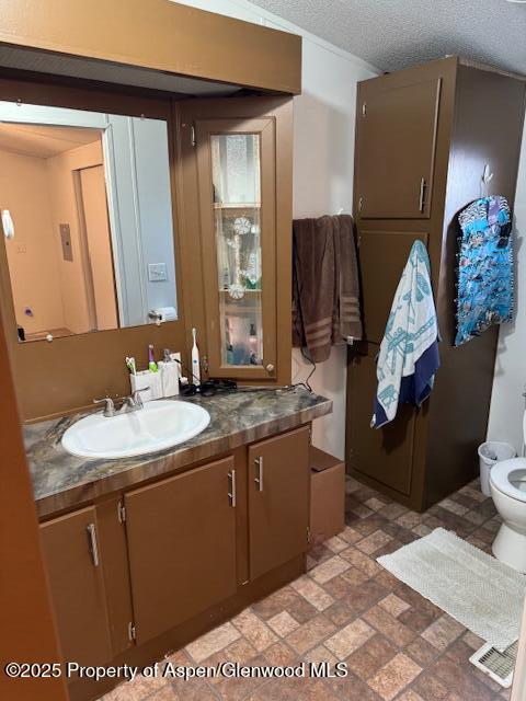 bathroom with brick patterned floor, visible vents, toilet, and vanity