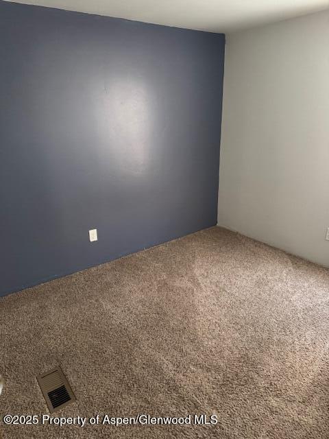 carpeted empty room featuring visible vents