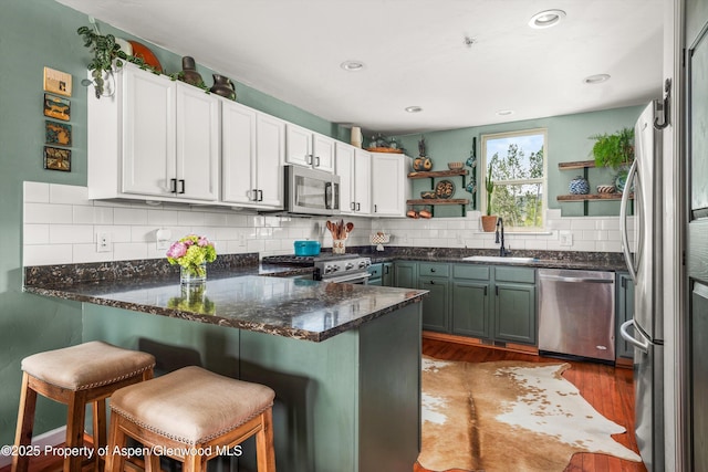 106 Lakeside Ct, Basalt, CO 81621 - kitchen featuring appliances with stainless steel finishes, open shelves, a peninsula, wood finished floors, and white cabinetry