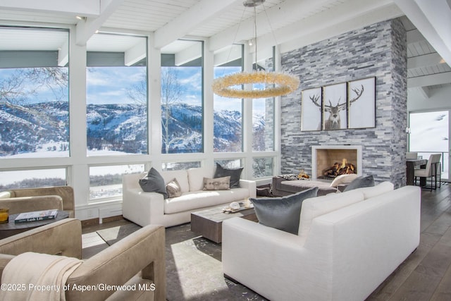 sunroom / solarium with a stone fireplace, beam ceiling, and a mountain view