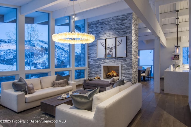 living room with a towering ceiling, a fireplace, dark wood finished floors, and beam ceiling