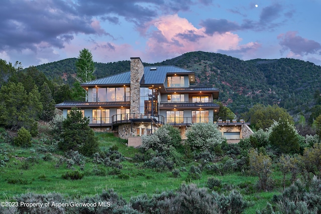 back house at dusk featuring a mountain view and a balcony