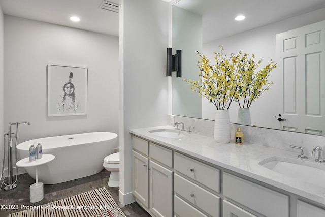 bathroom with a tub, hardwood / wood-style floors, vanity, and toilet