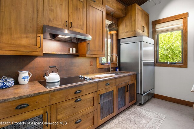 2701 County Rd 100, Carbondale, CO 81623 - kitchen with freestanding refrigerator, a sink, under cabinet range hood, black electric stovetop, and brown cabinets