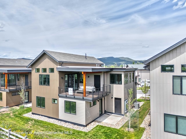 rear view of property with central AC unit, a mountain view, and a balcony