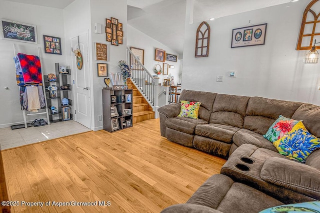 living area with stairway, wood finished floors, and lofted ceiling
