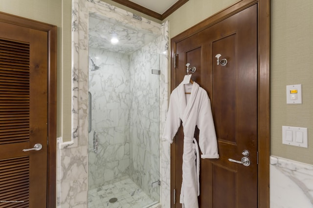 bathroom with a shower with shower door and crown molding